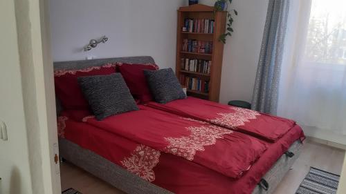 塞克希费黑瓦尔Veronika Apartment的卧室内的一张红色的床,设有书架