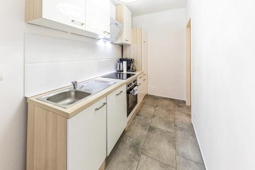 维也纳CENTRAL & AFFORDABLE by JR City Apartments的厨房配有白色橱柜和水槽