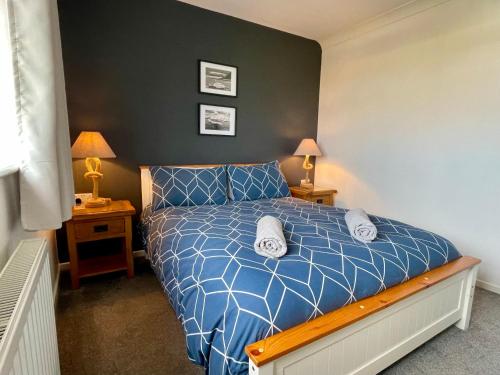 本莱赫Bungalow33 Benllech的一间卧室配有一张带蓝色棉被的床