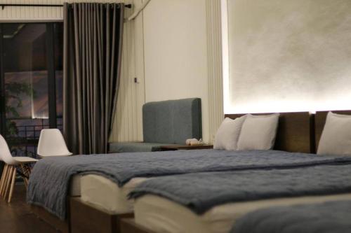 芹苴T-House的一间卧室配有一张带蓝色毯子和椅子的床