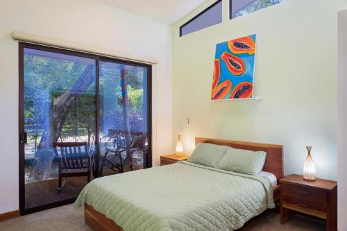 IguanaCasa Papaya - Eco Casita Phase 1-1的一间卧室设有一张床和一个滑动玻璃门