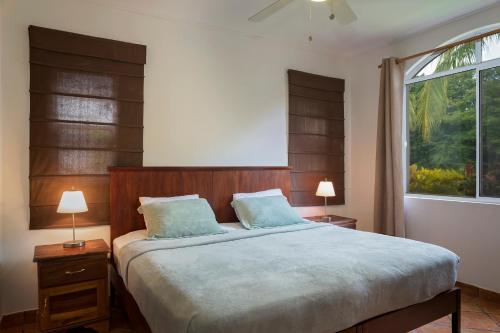 IguanaVillas Iguana A-13 Beachfront Condo的一间卧室配有一张带两盏灯的床和一扇窗户。