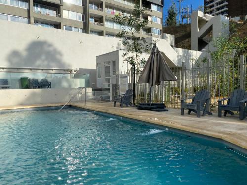 维纳德马Departamento en Viña del Mar的一个带遮阳伞和椅子的室外游泳池