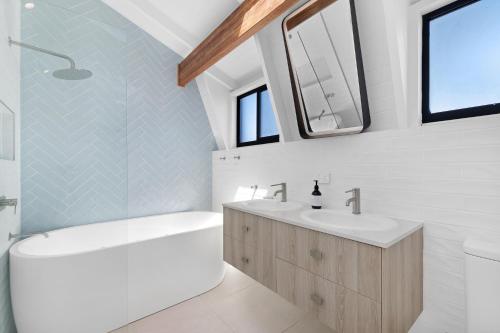 黄金海岸5BR Mermaid Waters Luxury Home的白色的浴室设有2个水槽、浴缸和浴缸。