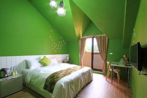 垦丁大街优闲民宿的绿色卧室配有床、书桌和电视