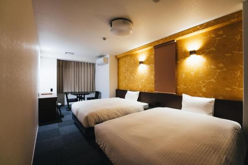 佐贺市TAPSTAY HOTEL - Vacation STAY 35228v的酒店客房设有两张床和一张桌子。