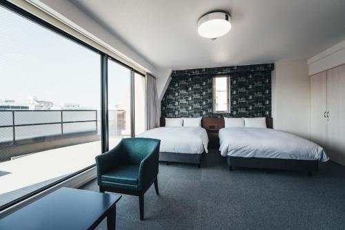 佐贺市TAPSTAY HOTEL - Vacation STAY 35227v的一间卧室设有两张床、一把椅子和一个窗户。