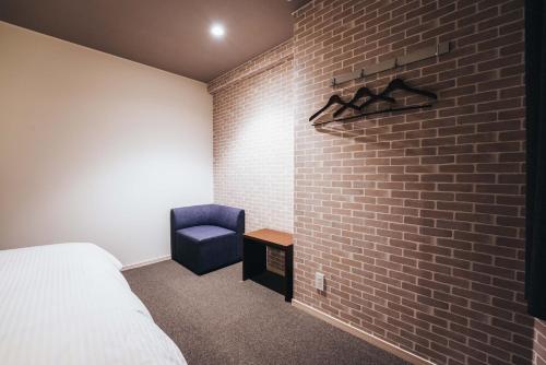 佐贺市TAPSTAY HOTEL - Vacation STAY 35238v的一间卧室设有砖墙和蓝色椅子