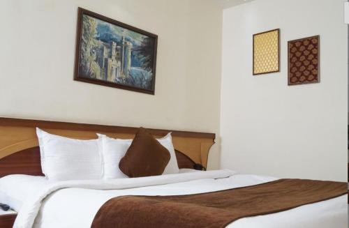 贾巴尔普尔BK Castles Hotel的卧室配有一张大床,墙上挂有两张照片