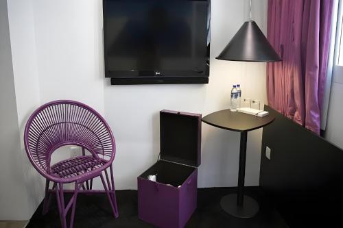 新加坡Hi Hotel Bugis的一间设有紫色椅子、桌子和电视的客房