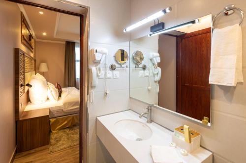 塔伊夫فندق زمان هوم لاند Zaman Homeland Hotel的一间带水槽和镜子的浴室以及一张床