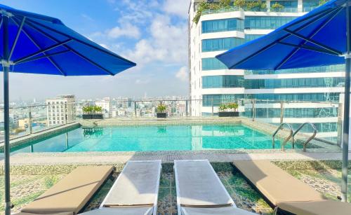岘港Palazzo 3 Danang Hotel的一座大楼内的游泳池,配有椅子和遮阳伞