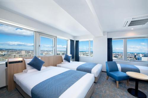 宫崎ART HOTEL Miyazaki Sky Tower的配有大窗户的酒店客房内的两张床