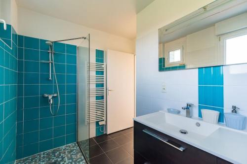 普卢阿La maison d'Alphonse : Plouha, proche de la plage的浴室设有水槽和蓝色瓷砖淋浴。