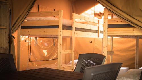 贝尔多夫Safari Tent XL Camping Belle-Vue的客房设有两张双层床和一张桌子及椅子。