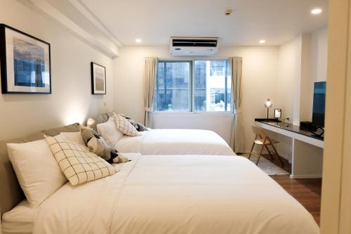 曼谷Upscale 3-bedroom 3-bathroom suite 1 min to BTS Prompong的配有书桌和电视的客房内的两张床