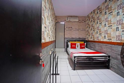 BungurasihOYO 91415 De Wijaya Hotel的小房间设有一张带红色枕头的床
