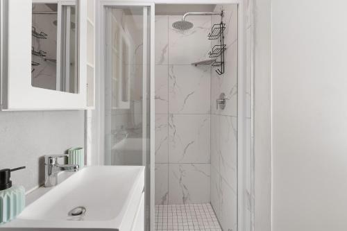 布鲁堡史特兰Nirvana 12的带淋浴和盥洗盆的白色浴室