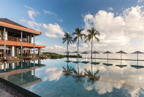 波普托Hansar Samui Resort & Spa - SHA Extra Plus的一个带棕榈树和遮阳伞的游泳池的度假酒店