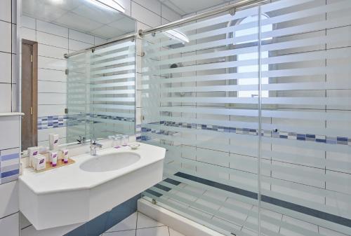 沙迦TIME Express Hotel Al Khan的一间带水槽和玻璃淋浴的浴室