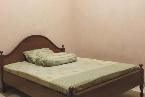 谏义里Griya Erlangga的一张带木制床头板的床,上面有枕头