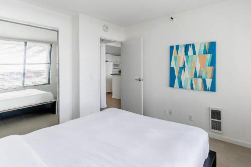 旧金山South Beach 1br w sun deck gym nr waterfront SFO-1658的卧室配有白色的床和墙上的绘画作品