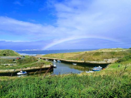 HartleyThe Waterford Arms的一条河,河里有船,天空有彩虹