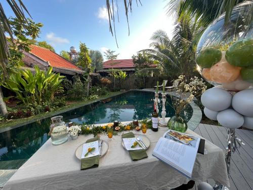 An Bàn (2)Pao Homes - An Bang Beach Stone Villa的游泳池旁带餐盘的桌子