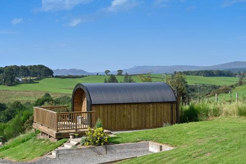 格拉斯哥Luxury Glamping Pods - The Heft & The Hirsel的田野中间的木结构建筑