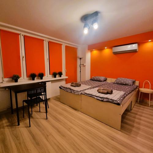 克拉科夫Orange Apartment Kraków的一间卧室设有橙色的墙壁、一张床和一张书桌
