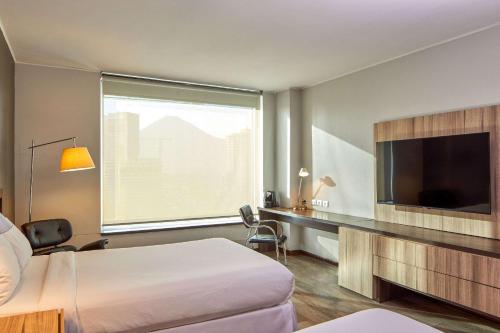 圣地亚哥Radisson Blu Plaza El Bosque Santiago的配有一张床和一台平面电视的酒店客房
