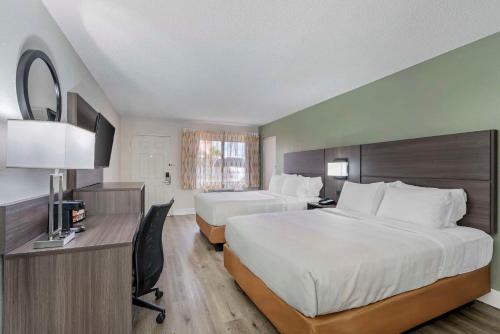 奥兰多Quality Inn & Suites Orlando East - UCF Area的酒店客房配有两张床和一张书桌