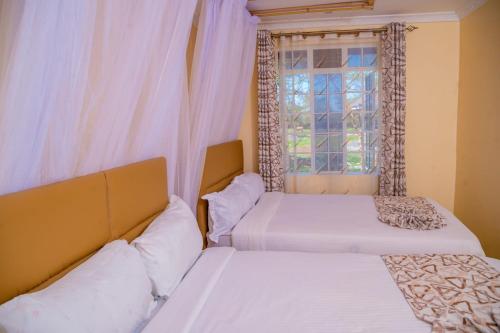AheroCalfie Resort Kisumu的带窗户的客房内的两张床