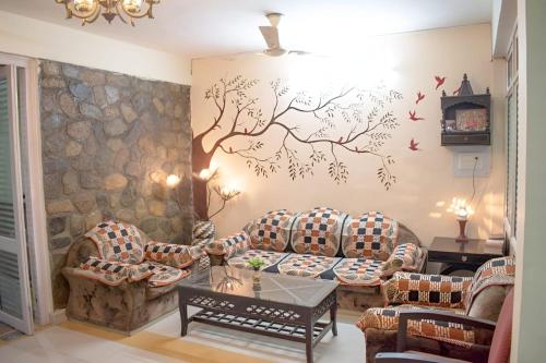 兰纳加Mannat Corbett Resort的客厅配有沙发,墙上挂着一幅树壁画