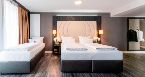 海德堡PLAZA Premium Heidelberg的一间卧室配有两张带白色床单和床头板的床。
