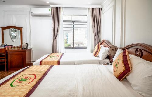 岘港Phu My Hai Hotel的酒店客房设有两张床和窗户。