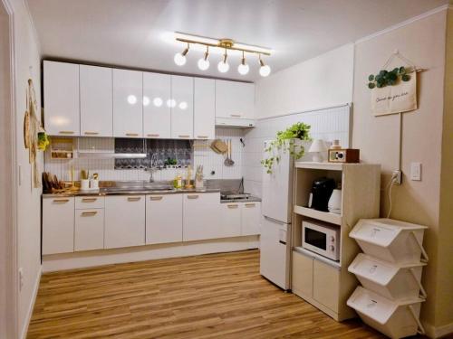 首尔Jamsil Heaven的白色的大厨房配有白色橱柜和木地板