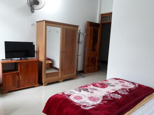 Bảo LạcKhách sạn Việt Hoàng的一间卧室配有一张床、一台电视和家具