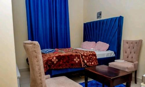 蒙巴萨Ziggon villa mtwapa的一间卧室配有一张带蓝色窗帘的床和一张桌子