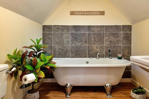 AberhafespFinest Retreats - Ty Nant的浴室设有白色浴缸,种植了植物。