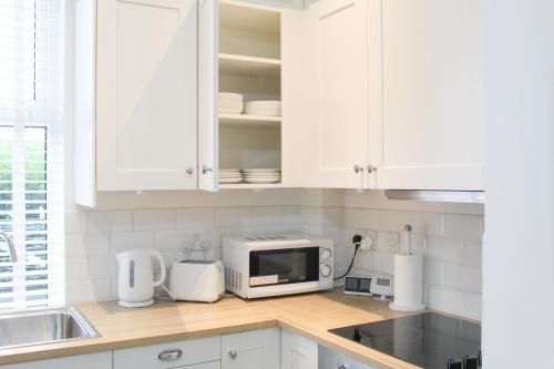 巴特利Cosy house in West Yorkshire的厨房配有白色橱柜和微波炉
