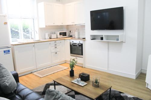 巴特利Cosy house in West Yorkshire的厨房配有白色橱柜、桌子和电视。