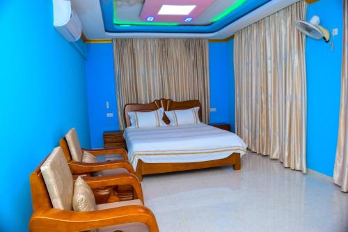 布琼布拉lake palace beach hotel的一间卧室配有一张床、两把椅子和一台电视