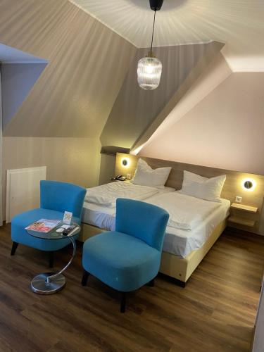 明斯特Hotel Feldmann的一间卧室配有一张床和两张蓝色椅子