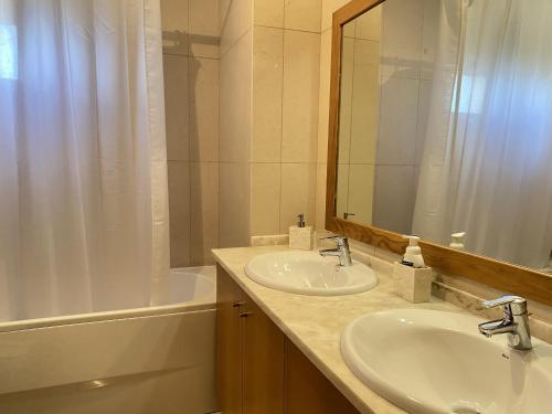 圣港Casa das Pedras Pretas的浴室设有2个水槽、浴缸和镜子