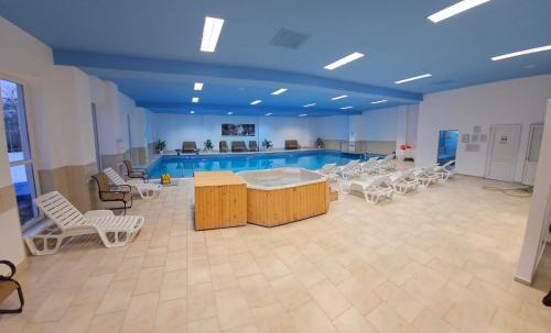 苏恰瓦皇家庄园的一个带白色桌椅的游泳池和一个游泳池