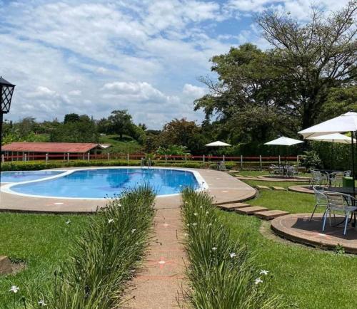 卡拉尔卡Finca Hotel Sol Y Luna的庭院内的游泳池,配有桌子和遮阳伞