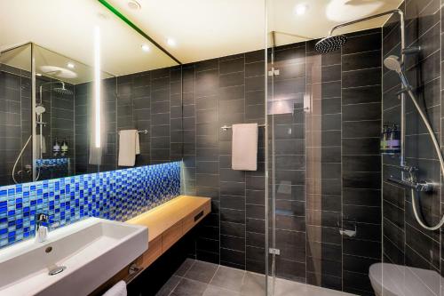 海尔布隆Premier Inn Heilbronn City Centre的浴室设有水槽和蓝色瓷砖淋浴。