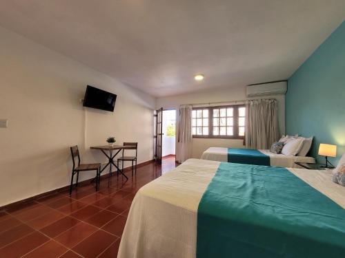 博卡奇卡Calypso Beach Hotel by The Urbn House Santo Domingo Airport的酒店客房带两张床和一张桌子以及椅子。