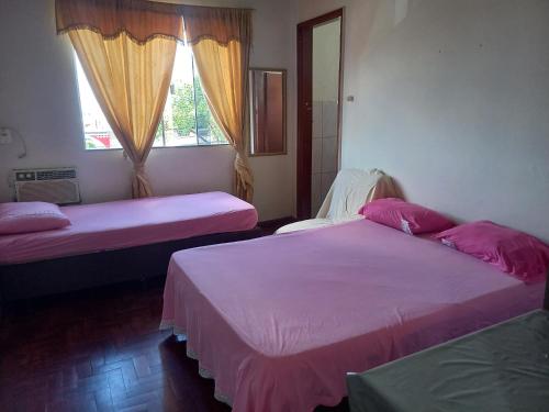 Cruzeiro do OesteHotel da Gaucha的配有粉红色床单和窗户的客房内的两张床